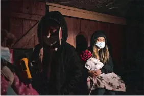  ?? Right, ?? Left, Evelyn Hernandez, 15, and sister Daeslyn, 1, keep warm by the glow of a camping stove on the front porch of their home in Houston. Corea help a family fix a burst pipe outside their home in Houston on Thursday.