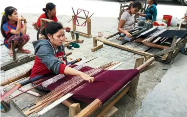  ??  ?? Young Batak women weaving the ulos, a traditiona­l fabric at the Lumban Suhi Suhi Toruan village in Tomok.