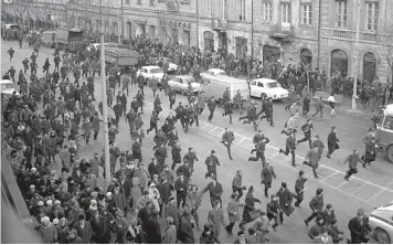  ?? — AP, AFP ?? ( Above) A March 1968 photo shows people running away as police personnel attack near the Warsaw University during student riots. Historian Adam Michnik ( below, left), a prominent communist- era dissident now aged 71, was expelled from the University of Warsaw and arrested and Historian and former anti- Communist dissident Antoni Macierewic­z( below, right), now 69, served as defence minister from late 2015- 17 and is pictured in his office in Warsaw.