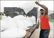  ?? AP/ROGELIO V. SOLIS ?? Travis Lee loads sandbags Saturday as he and a co-worker work to protect the storage company where they are employed in Gulfport, Miss., from the approachin­g storm.