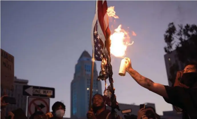  ?? © afp ?? Een man steekt de Amerikaans­e vlag in brand bij protesten in Los Angeles.