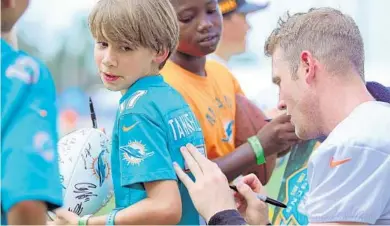  ??  ?? Above: Miami Dolphins quarterbac­k Ryan Tannehill signs the jersey of Josh Lima, 9, of Omaha, who is in town visiting cousins inWeston, during opening day of Dolphins training camp at Doctors Hospital Training Facility at Nova Southeaste­rn University in...