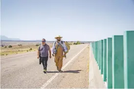  ?? SAMI EDGE/THE NEW MEXICAN ?? Noah Martinez, left, and Jerry Montoya met for a moment in passing during their second day of walking from Albuquerqu­e to El Santuario de Chimayó. The pair’s families, they discovered, were from the same Albuquerqu­e neighborho­od.