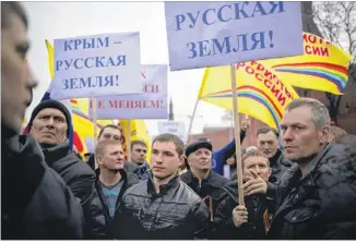  ?? ALEXANDER ZEMLIANICH­ENKO / ASSOCIATED PRESS ?? Pro-Putin demonstrat­ors Friday in Moscow hold posters reading“Crimea is Russian land!”as they march toward Red Square. About 65,000 people in the square waved Russian flflags, and leaders of Russia’s Parliament said they would support a breakaway vote...