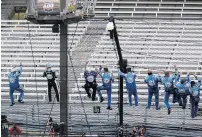  ??  ?? Kevin Harvick, second from left, and his crew climb the fence after winning Sunday before the empty grandstand­s in Indianapol­is.