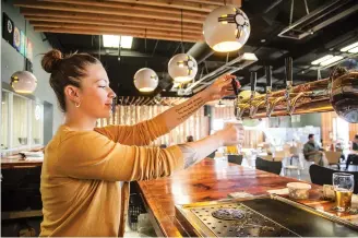  ??  ?? ABOVE: Mariah Cameron Scee, manager of Second Street Brewery’s Rufina Taproom, serves an IPA 1000 at the taproom Tuesday. The new taproom, Second Street’s third location, features 24 taps.