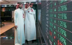  ?? — Bloomberg ?? Visitors watch stock movements displayed on video screens inside the Saudi Stock Exchange, also known as the Tadawul All Share Index, in Riyadh. A poll found 62 per cent of managers expect to raise their investment in Saudi stocks over the next three...