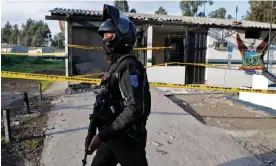  ?? ?? A police officer stands guard at the El Blanqueado community police unit in southern Quito, on 11 January, a day after an explosion damaged the station. Photograph: AFP/Getty Images