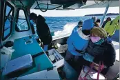  ?? ROBERT F. BUKATY — THE ASSOCIATED PRESS ?? Nurses Kathy Cheney, wearing a hat, and Maureen Giffen huddle on a wet and windy ride aboard a lobster boat on the way to set up a COVID-19 vaccinatio­n clinic Friday on Great Cranberry Island, Maine.