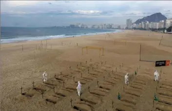  ?? Leo Correa/Associated Press ?? Activists in costume dig symbolic graves Thursday on Copacabana Beach as a protest against the Brazilian government’s handling of the COVID-19 pandemic in Rio de Janeiro.