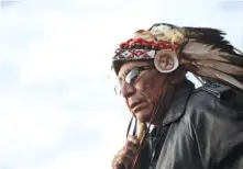  ??  ?? Chief Arvol Looking Horse, a spiritual leader of the Great Sioux Nation, puts on his headdress last month for an interfaith ceremony at the Oceti Sakowin camp where people have gathered to protest the Dakota Access oil pipeline in Cannon Ball, N.D.