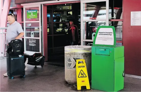  ?? REGINA GARCIA CANO / THE ASSOCIATED PRESS FILES ?? Travellers at McCarran airport in Las Vegas pass a green metal container designed for disposal of recreation­al drugs. Known as “amnesty boxes,” there are 20 of them scattered around the airport and its rental car centre.