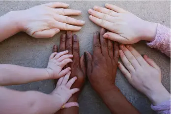  ?? (AP Photo/Tsvangiray­i Mukwazhi) ?? Joyce Muchenje, centre, places her hands on a wall and that of her three children, who all have albinism, outside their family home in Chitungwiz­a on the outskirts of Harare, in this Tuesday, June, 9, 2020 photo. Muchenje used to provide for them by washing laundry and household cleaning for cross border traders at a busy border town before the lockdown, but now the border trade has stopped and Mutenje has run out of money to get the skin cream for her children.