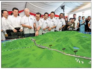  ?? AP ?? Then-Malaysian Prime Minister Najib Razak (third from left) looks at a model of the East Coast Rail Link during a promotiona­l event last September for the project in Kuantan, Malaysia. The rail line now is canceled.
