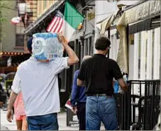  ?? Will Waldron / Times Union ?? Cases of bottled water are carried into a Broadway restaurant after a boil water advisory on Friday. The order was lifted by the state on Saturday.
