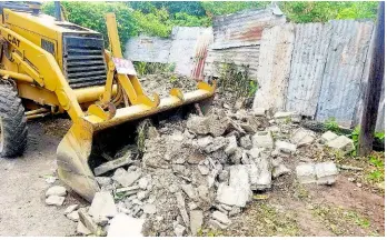  ??  ?? Bulldozer allegedly sent to destroy sections of the wall separating 4A and 4B Shortwood Road. The Full Truth Church of God Deliveranc­e Centre is located at 4A. An elderly couple resides at 4B.