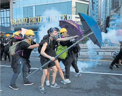  ??  ?? CONFLICT: Protesters use umbrellas to shield themselves from tear gas fired by policemen