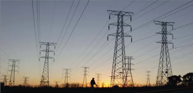  ??  ?? MISGUIDED STANCE: A man walks past electricit­y pylons as he returns from work in Soweto. According to the president, says the writer, it is the roll-out of electricit­y infrastruc­ture to those – overwhelmi­ngly from the ranks of the black, poor working class – that were excluded from the grid before 1994, that is to blame for South Africa’s current power crisis.