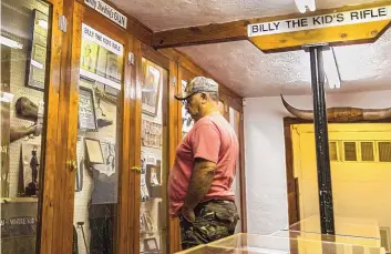  ??  ?? Salvador Vargas of Chihuahua, Mexico, looks at a Winchester rifle, reportedly once owned by the Kid, during a stop at the Billy the Kid Museum in Fort Sumner. According to the museum, 25,000 people tour the collection­s here each year.