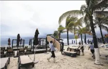  ?? Elizabeth Ruiz / AFP / Getty Images ?? Hotel workers collect beach loungers before Tropical Storm Nate arrives in Cancun, Mexico, in the Yucatan Peninsula.