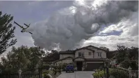  ?? David McNew / Getty Images ?? A firefighti­ng aircraft makes a drop to protect a house Sunday from a wildfire near Burbank, Calif. Evacuation orders have been issued for the area.