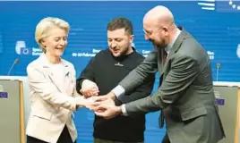  ?? OLIVIER MATTHYS/AP ?? European Commission President Ursula von der Leyen, left, Ukraine’s President Volodymyr Zelenskyy and European Council President Charles Michel join hands Thursday during an EU summit in Brussels as Zelenskyy wrapped up a rare trip outside Ukraine.