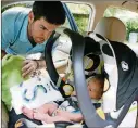  ?? CHRIS DUNN / CDUNN@AJC.COM ?? Kevin Skelly, of Roswell, makes sure 2-week-old Liam is comfortabl­e and secured in his car seat before driving him and wife Kelly to the grandparen­ts’ house.