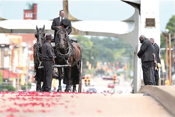  ?? CURTIS COMPTON/ ATLANTA JOURNALCON­STITUTION/TNS ?? JULY 26: Family members bow their heads as horse-drawn carriage carrying the body of Rep. John Lewis pauses for a minute of silence at the crest of the Edmund Pettus Bridge, site of the historic 1965 voting rights marches, in Selma, Ala.