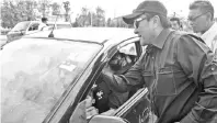  ??  ?? Bobbey (right) attaching a sticker on one of the vehicles during the Road Safety Campaign, yesterday.