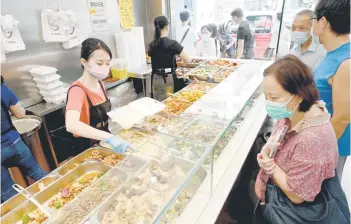  ?? ?? Photo shows customers being served low-priced two-dish mealboxes at Kitty Chan’s restaurant in Hong Kong.