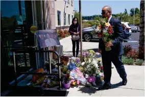  ?? AP PHOTO BY ASHLEY LANDIS ?? A man places flowers at a memorial honoring Dr. John Cheng sits outside his office building on Tuesday, May 17, 2022, in Aliso Viejo, Calif. Cheng, 52, was killed in Sunday’s shooting at Geneva Presbyteri­an Church.