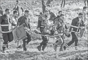  ??  ?? Palestinia­n paramedics carry a wounded protester on a stretcher during clashes with Israeli forces following a demonstrat­ion near the fence along the border with Israel, east of Gaza City. — AFP photos