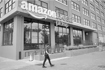  ?? — AFP photo ?? A man walks past an AmazonFres­h Pickup location on June 16, in Seattle, Washington. With its US$14 billion purchase of grocery chain Whole Foods Market Inc, the largest e-commerce company announced its intention to take on Wal-Mart in the...