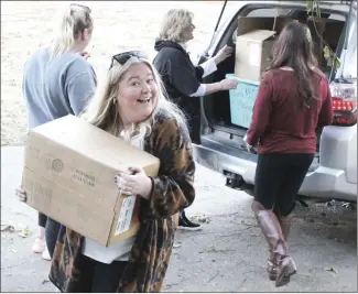  ?? Katie West • Times-Herald ?? Cara McCollumn Birthday Book alumni volunteers unload boxes of books for the Junior Auxiliary of St. Francis County’s Angel Tree Project. Each year the two groups join forces to bring books to children for Christmas. Above, Halle Foust smiles for the camera as she works with fellow Birthday Book members, LuLu Foust, Maureen McCollum and JASFC Angel Tree Chair Caitlyn Sweet to bring books inside the Campbel House.