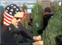  ??  ?? Patriot Guard Rider Cyndi Owen, of Rock City Falls, attaches a paper ornament to a Christmas tree during a Trees for Troops effort at Ellms Family Farms on Monday.