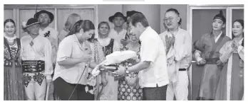  ?? ?? BAYANIHAN Executive Director Marielle Javellana and Erehwon Foundation president Jesus Varela (center) exchange gifts on behalf of their respective organizati­ons