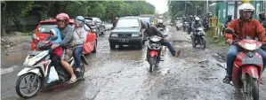  ?? UMAR WIRAHADI/JAWA POS ?? LUBANG BESAR: Kondisi Jalan Mayjen Sungkono yang rusak parah di sisi Desa Segoromadu, Kebomas, kemarin. Pengendara motor harus berhati-hati saat melewatiny­a.