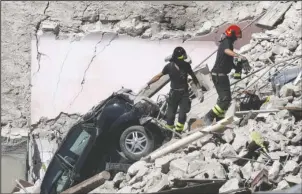  ?? The Associated Press ?? RUBBLE: Rescuers make their way through destroyed houses following Wednesday's earthquake on Thursday in Pescara Del Tronto, Italy. Rescue crews raced against time Thursday looking for survivors from the earthquake that leveled three towns in central...