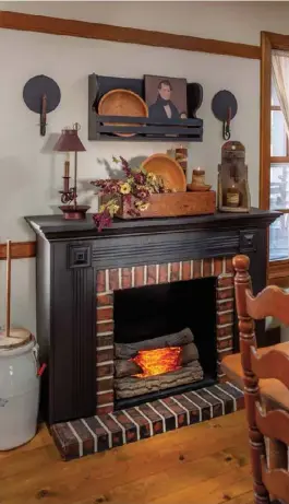  ??  ?? Below: Scored at a rummage sale, the dining room’s faux fireplace is a good example of the couple’s treasure-hunting prowess. They painted the formerly white piece black for a prim look and added a matching plate rack above to display portraits and wooden accent pieces.