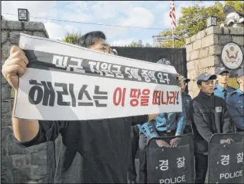  ?? Chun Jin-hwan The Associated Press ?? A college student holds a banner Friday in front of the U.S. ambassador’s residence in Seoul, South Korea. The sign reads “(Harry) Harris, leave this land!”