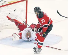  ??  ?? The Devils’ Kyle Palmieri scores against Red Wings goalie Jimmy Howard.