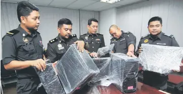  ??  ?? MDTCC Seberang Perai Tengah branch deputy head Mohd Syakir Abdul Wahab (second left) together with his officers showing the seized computers during a press conference. — Bernama photo