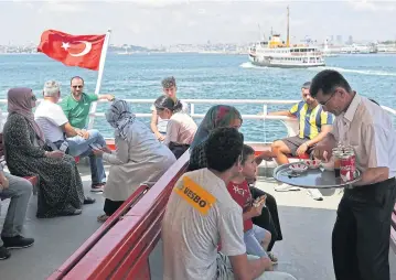  ?? EPA ?? A waiter serves soft drinks to passengers crossing the Bosphorus on a ferry, in Istanbul, Turkey on Thursday.