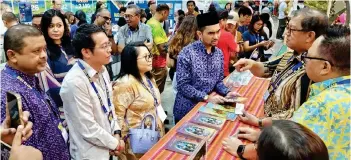  ?? ?? Deputy Minister of Tourism, Arts and Culture Khairul Firdaus Akbar Khan and tourism officials visit the Sabah Tourism Board (STB) booth, with its chairman Datuk Joniston Bangkuai briefing on offerings. STB chief executive officer Julinus Jeffrey Jimit also present.