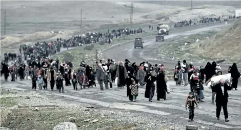  ?? ARIS MESSINIS/GETTY IMAGES ?? Iraqi families walk down a road as they flee Mosul on Friday, during an offensive by security forces to retake the western half of the city from Islamic State fighters.