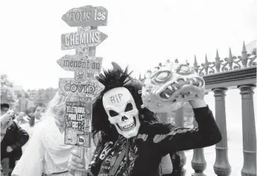  ?? SAMEER AL-DOUMY/GETTY-AFP ?? Protests in France: A protester wearing a mask of a human skull holds a sign in French reading “All the roads lead to COVID” during protests in Paris on Saturday against the vaccinatio­n and the compulsory health pass called for by the French government. Some 160,000 people took to the streets as legislator­s debated the virus bill.