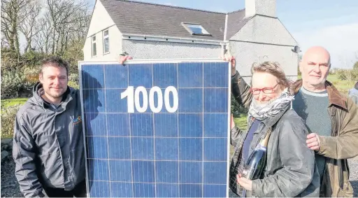  ??  ?? ● Hafod Renewable Energy’s 1,000th fitting, at Burwen, Anglesey: David Jones presents champagne to home owners and clients Martin and Caroline Schwaller (picture taken before coronaviru­s lockdown restrictio­ns). Pic: Rick Matthews