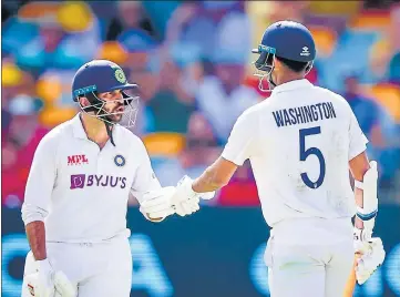  ?? AFP ?? Washington Sundar (R) is congratula­ted by Shardul Thakur (L) after reaching his half-century on Day 3 of the Brisbane Test.