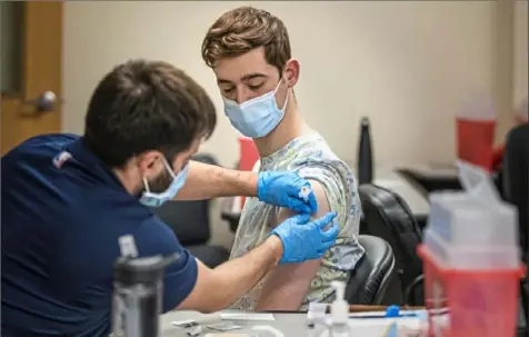  ?? Andrew Rush/Post-Gazette ?? Kyle Rodriguez, 23, of the South Side, gets his first dose of the Moderna vaccine from pharmacist Jerry Pasquale on Tuesday at Pittsburgh Mercy on the South Side.