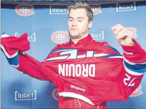  ?? CP PHOTO ?? Newly-acquired Montreal Canadien Jonathan Drouin puts on his jersey as he is introduced to the media during a press conference at the Bell Centre in Montreal on Thursday.